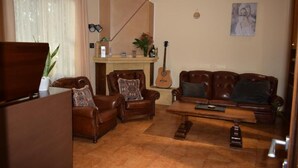 A living room with a brown leather sofa, a wooden coffee table, a brown leather armchair, a brown leather sofa, a guitar, a fireplace, and a television. - Ad Ricezioni Villa Francesca (San Demetrio Corone)