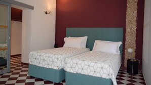 A room with two beds, a checkered floor, a red accent wall, and a decorative column. - Ad Ricezioni Villa Francesca (San Demetrio Corone)