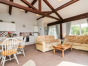 A living room with a sofa, a wooden coffee table, and a dining area with chairs and a table. - Swallows: A Charming Retreat in Ventnor (Ventnor)