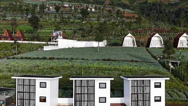 A rural landscape with terraced fields, white houses, and a mountain in the background. - Krincing Hills Cabin (Kebonlegi)