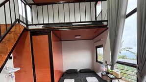 A compact room with a bunk bed, a small desk with a chair, a window with curtains, and a wooden floor. - Krincing Hills Cabin (Kebonlegi)