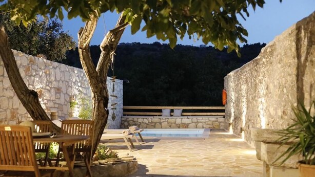 Eine Terrasse im Freien mit Steinboden, Holzmöbeln und einer Steinmauer.