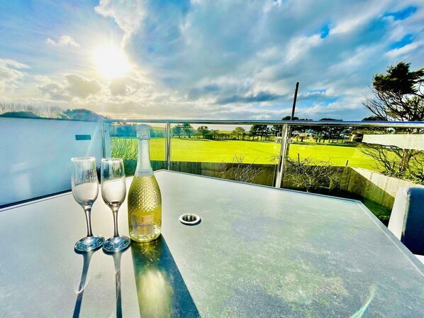A balcony with a table, two wine glasses, and a bottle of wine. - Avalennek, St Newlyn East (Newquay)