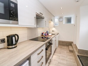 Eine moderne Küche mit Mikrowelle, Wasserkocher, Backofen und einer Holzarbeitsplatte.