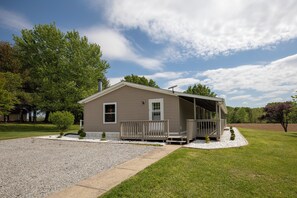 A single-story house with a covered porch, a gravel driveway, and a well-maintained lawn.