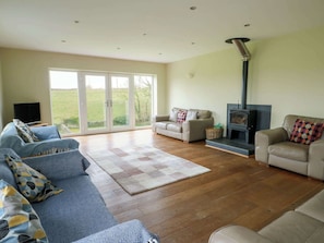 A spacious living room with a sofa, a chair, a fireplace, and a television.