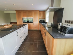 A modern kitchen with wooden cabinets, a black countertop, and a built-in oven.