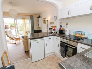 A compact kitchen with white cabinets, a dishwasher, a microwave, and a coffee maker. - Buddleia Cottage, Seaview (Seaview)