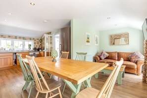 Eine geräumige Küche mit Holztisch und -stühlen, einem Essbereich und einem Wohnzimmer mit einer Couch.