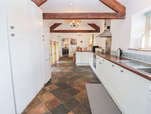 A kitchen with white cabinets, a wooden countertop, a tiled floor, and a visible chimney.