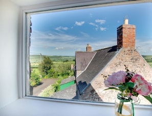 A window view of a stone building with a brick chimney, a green roof, and a clear sky. - Braeside within High Humbleton (Wooler)