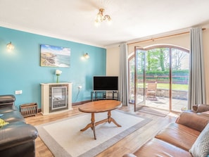 Ein Wohnzimmer mit Fernseher, Kamin, Sofa und großem Fenster.