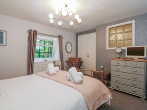 A bedroom with a bed, a dresser, a chair, a window, and a ceiling light fixture. - Happy Daze in West Runton. TV. (Cromer)