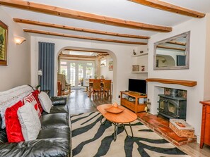 Ein Wohnzimmer mit einer Couch, einem Fernseher, einem Kamin und einem Essbereich mit Stühlen und einem Tisch.