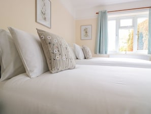 A bedroom with two beds, a window with curtains, and wall art. - Bower View: Cozy Retreat with Woodburner (Hereford)