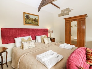 A bedroom with a bed, a wooden wardrobe, a nightstand, a lamp, and a painting on the wall. - Sheep Pen Cottage, Durham (Durham)