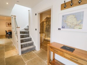 A staircase leading to a bathroom with a glass shower enclosure, a wooden console table with a book, and a map on the wall. - Cae Sam: Charming Retreat in Pentraeth (Pentraeth)