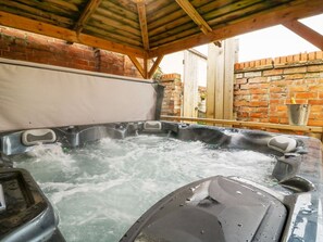 Un jacuzzi con techo de madera y paredes de ladrillo.