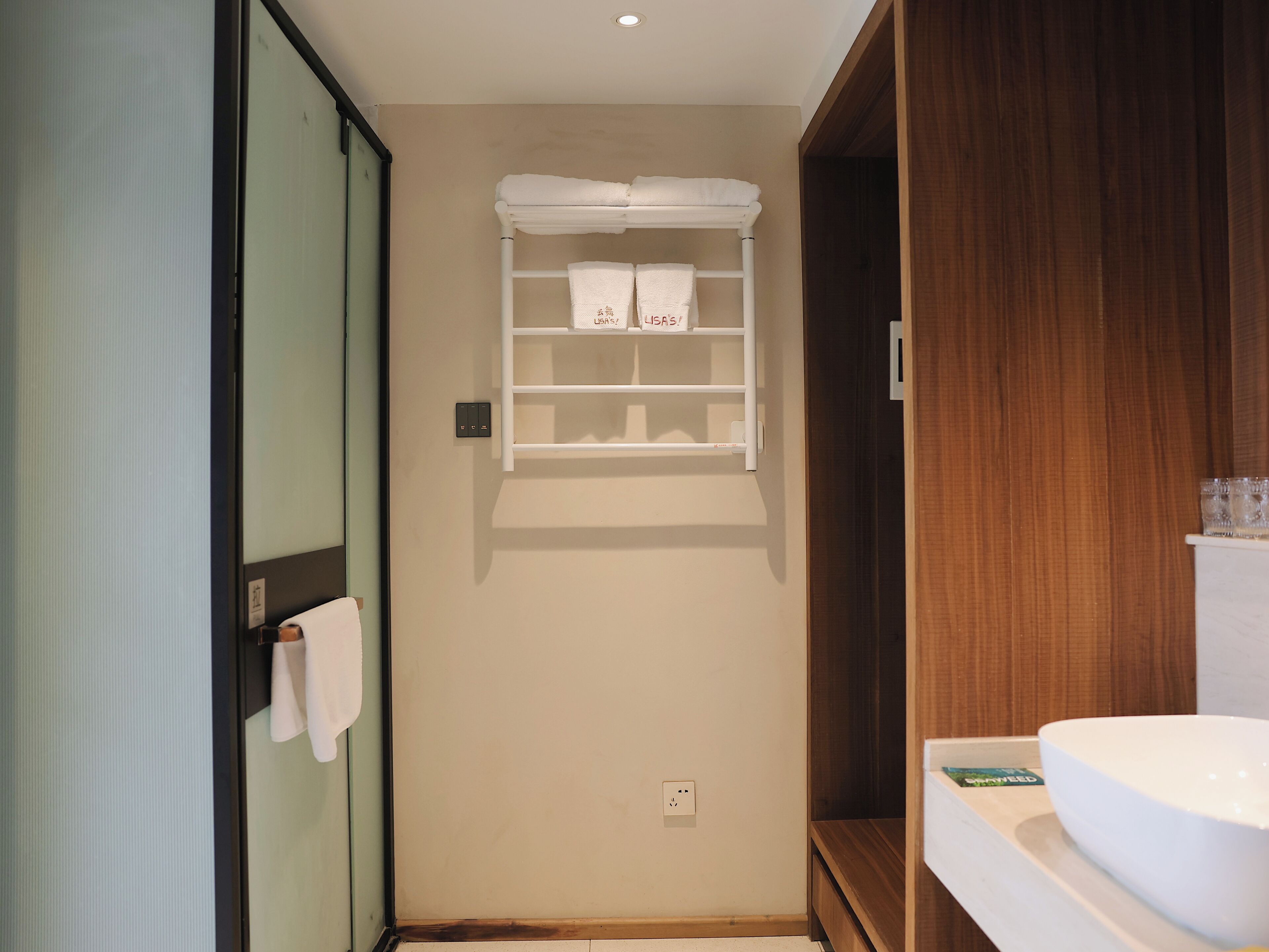 A bathroom with a white sink, a towel rack, and a wooden cabinet.