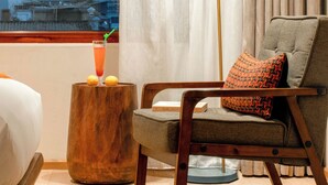 A hotel room with a bed, a chair with a cushion, a small wooden stool, a floor lamp, and a view of a mountain. - Yangshuo Lisa Boutique Hotel (Guilin)