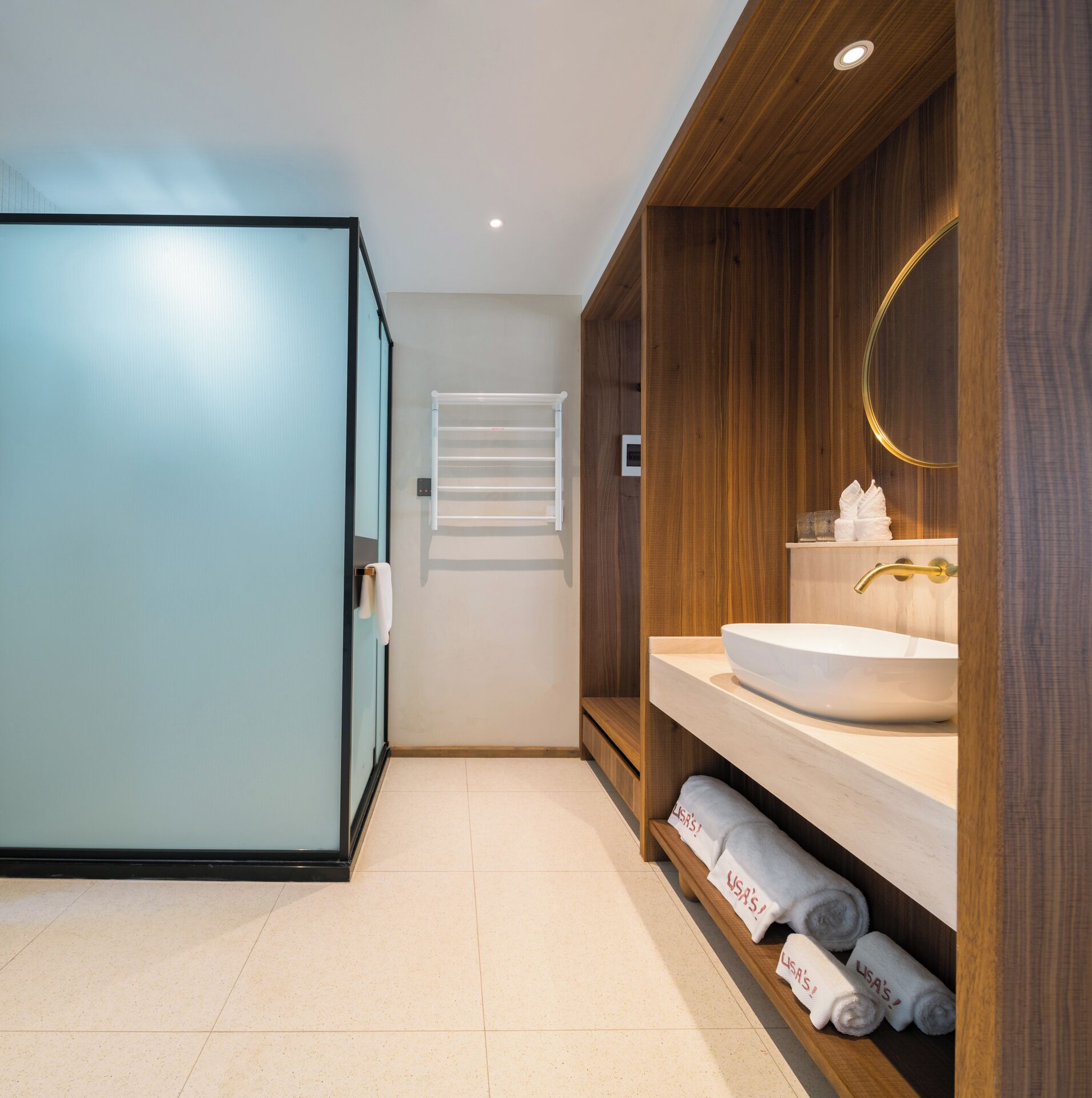 A modern bathroom with a large mirror, a sink, and a towel rack.