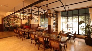 A dining area with multiple tables and chairs, a large window with a view, and a decorative plant. - Yangshuo Lisa Boutique Hotel (Guilin)