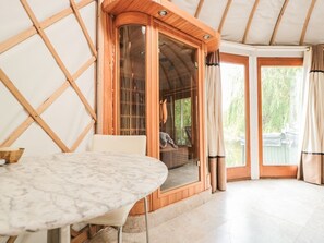 A room with a marble table, wooden door, and a view of greenery outside. - Island Yurt, Beckford (Tewkesbury)