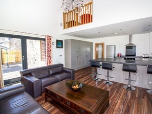A modern living room with a sofa, a coffee table, and a kitchen area with a bar and cabinets. - Nef-Stedi, Inverurie (Inverurie)