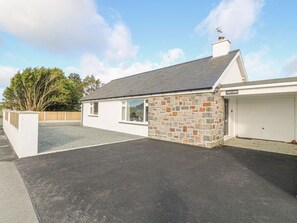 A single-story house with a garage, a stone wall, and a paved driveway.