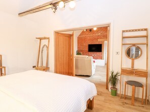 Ein Schlafzimmer mit einem großen Bett, einem Holzschrank, einem Spiegel und einer Ziegelwand im Hintergrund.