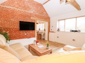 Ein Wohnzimmer mit Backsteinwand, Flachbildfernseher, Couchtisch aus Holz und einer Couch.