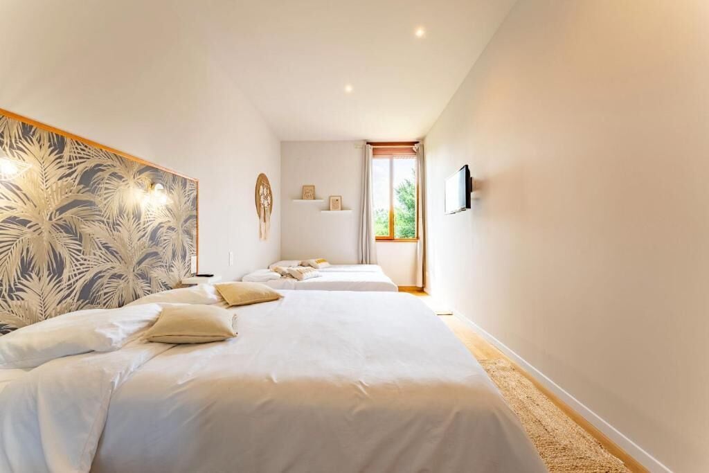 Habitación de hotel con dos camas, una obra de arte grande en la pared, un televisor de pantalla plana y una ventana con cortinas.