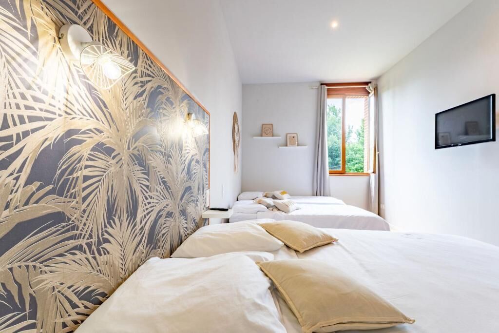 A hotel room with two beds, a large window, a wall-mounted TV, and a decorative wall panel.