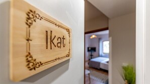 Un letrero de madera con la palabra 'Ikat' sobre una pared blanca.