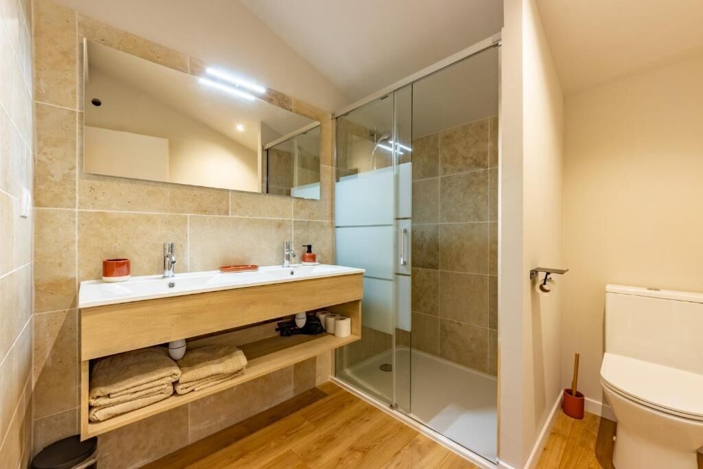 A bathroom with a shower, a sink with a mirror, and a toilet.