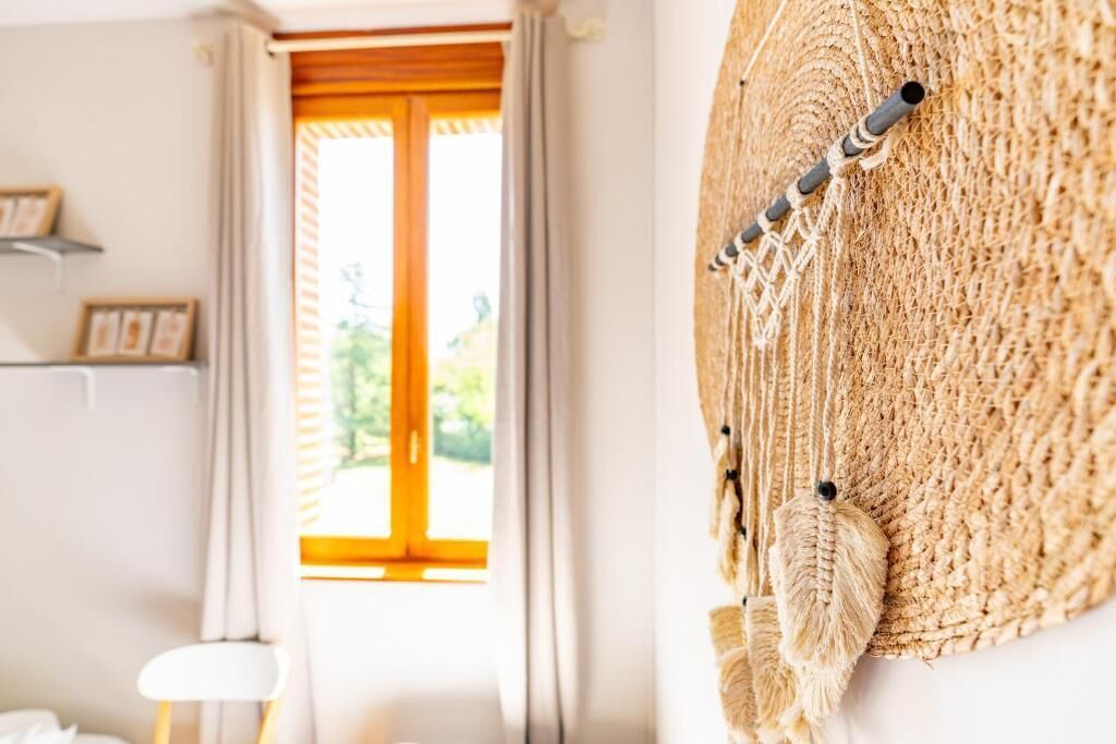 Una habitación con un ventanal grande, una silla blanca y un adorno en la pared.