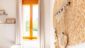 Una habitación con un ventanal grande, una silla blanca y un adorno en la pared.