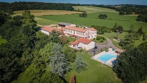 Vista aérea de una extensa propiedad con varias construcciones, una piscina y vegetación circundante.