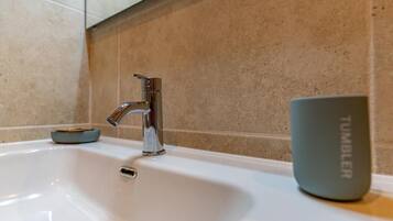 A bathroom sink with a modern faucet, a soap dish, and a tumbler.