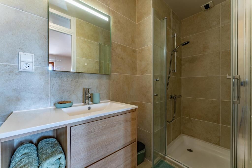 Ein Badezimmer mit Waschbecken, Spiegel und Dusche.