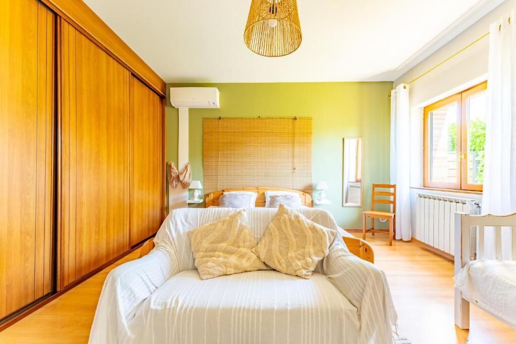 Une chambre à coucher avec un lit, une armoire en bois, une fenêtre avec des rideaux et un radiateur.