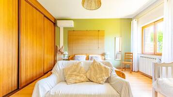Une chambre à coucher avec un lit, une armoire en bois, une fenêtre avec des rideaux et un radiateur.