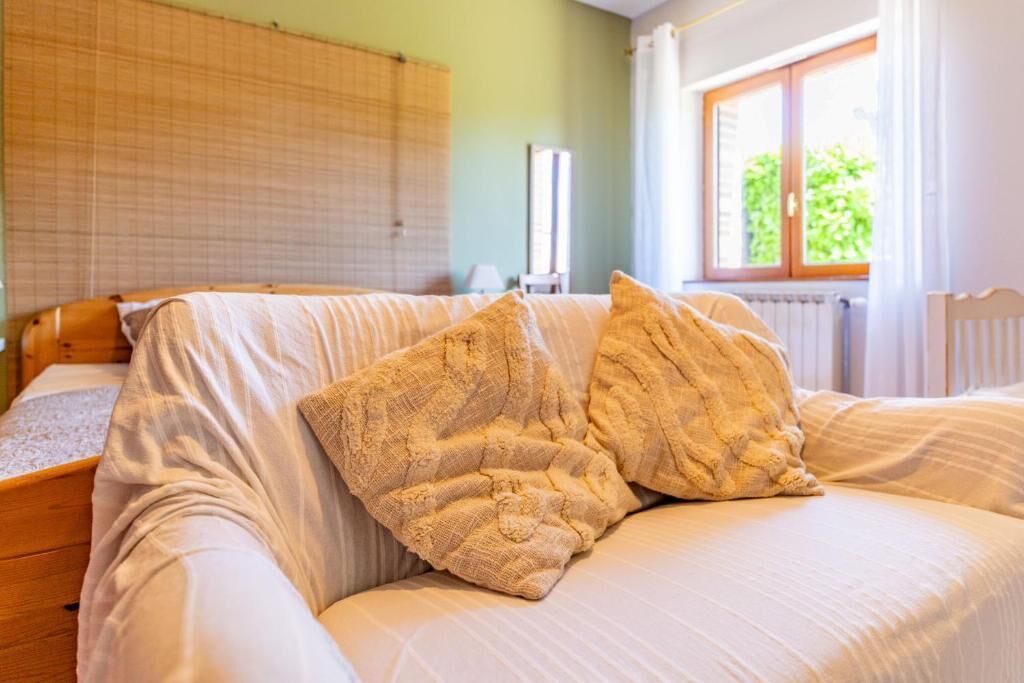 A bedroom with a bed, a window with curtains, and a radiator.