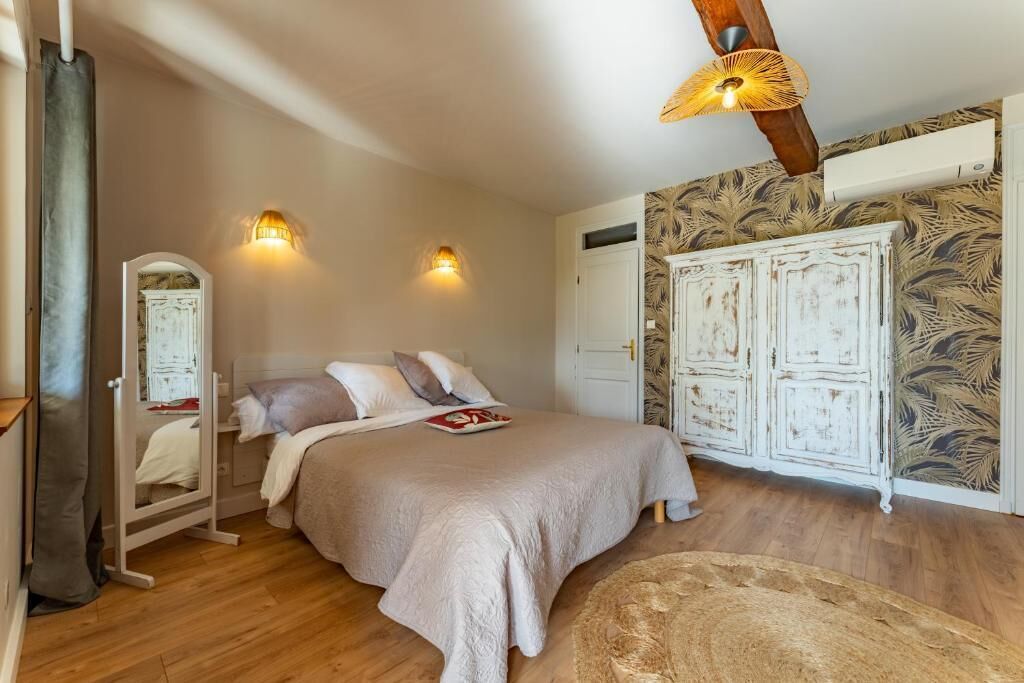 A bedroom with a bed, two wall-mounted lights, a wardrobe, and a mirror.