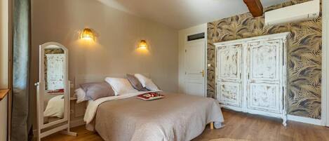 Ein Schlafzimmer mit einem Bett, zwei Wandleuchten, einem Kleiderschrank und einem Spiegel.
