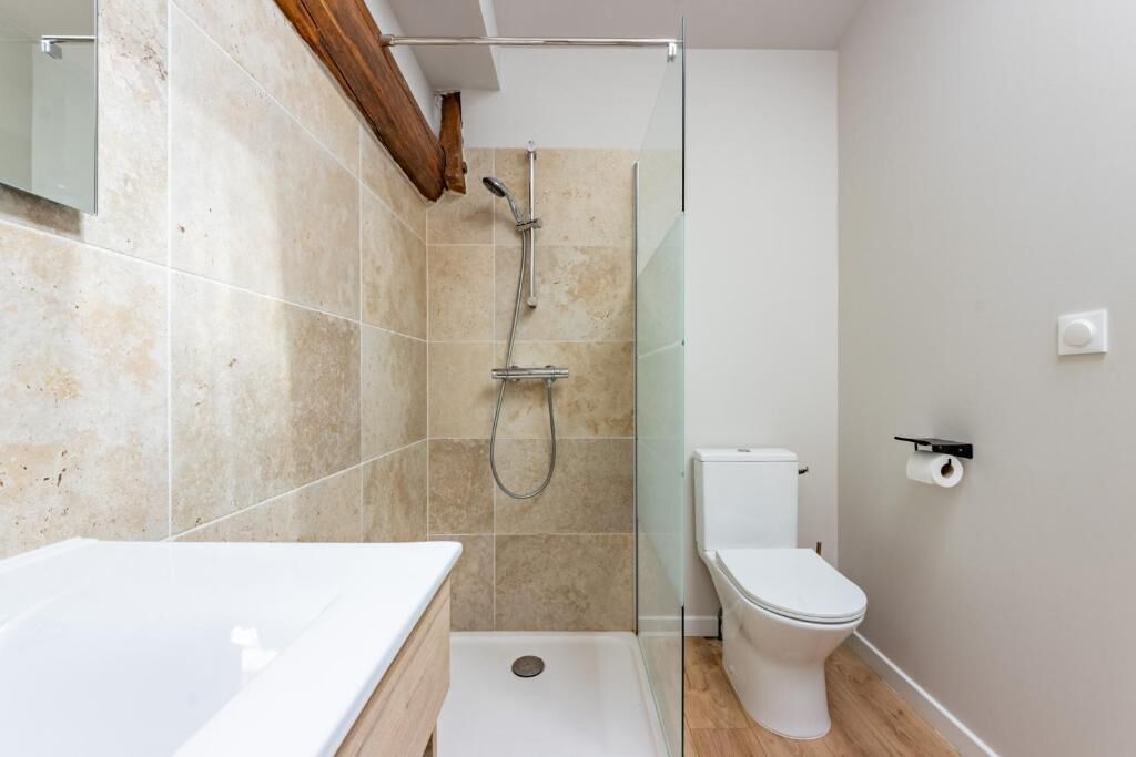 Une salle de bain moderne avec une douche à parois de verre, des toilettes blanches et un lavabo blanc.