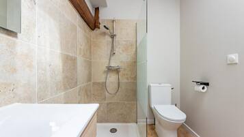 Un baño moderno con cabina de ducha de vidrio, inodoro y lavamanos blancos.