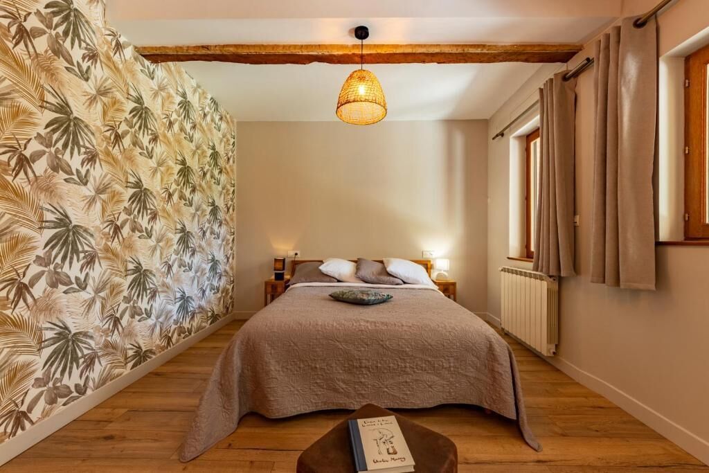 Un dormitorio con cama, lámpara colgante, radiador y ventana con cortinas.