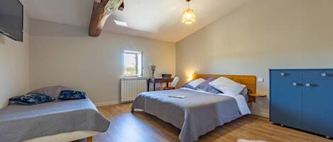A bedroom with two beds, a wooden ceiling beam, a radiator, a window, and a blue wardrobe.