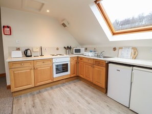 A kitchen with wooden cabinets, a microwave, a kettle, and a sink. - Wallace, Kinloch Rannoch (Pitlochry)